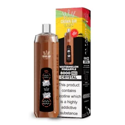 Dispositivo de vapeo desechable Al Fakher Crown Bar 8000 Pro Crystal marrón junto a su colorida caja de venta al por menor con la etiqueta Watermelon Pineapple 8000 Pro Crystal; la caja muestra una advertencia sanitaria sobre la nicotina.